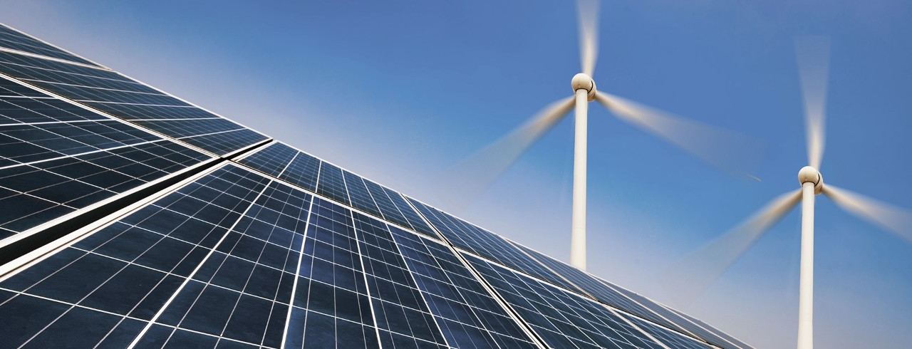 Solarpannels mit Windkrafträdern im Hintergrund