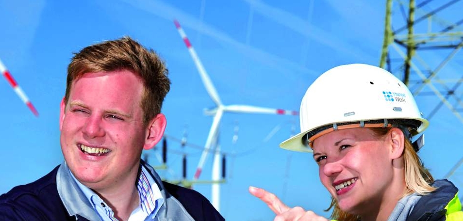 Mann und Frau im Gespräch vor Windrädern und Strommast