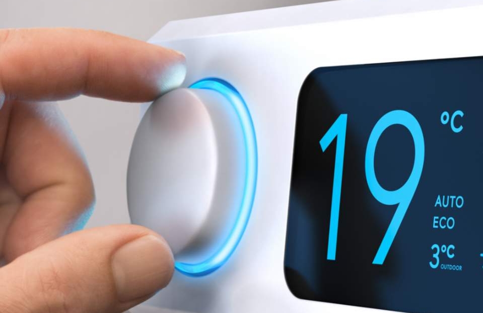 Digitaler Heizungsregler und eine Hand die ihn bedient